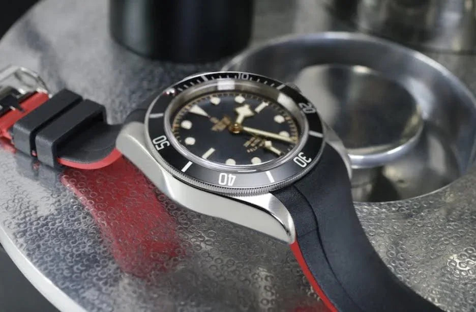 Montre de luxe avec bracelet caoutchouc noir et rouge sur table métal, accessoire misterchrono.com