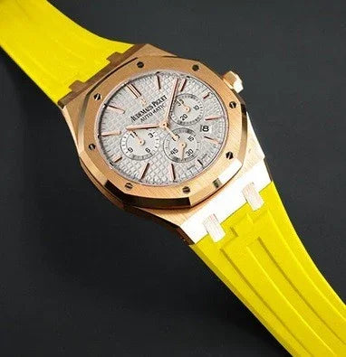 Montre de luxe avec boîtier doré, cadran argent, bracelet silicone jaune, accessoire horloger haut de gamme.