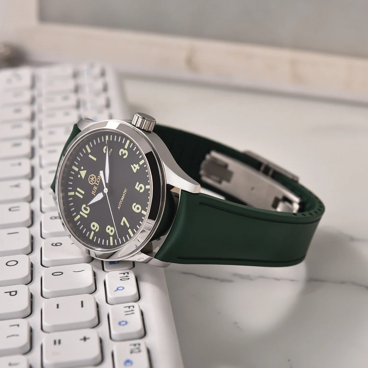Montre automatique avec bracelet vert posée sur clavier, accessoire luxe misterchrono.com