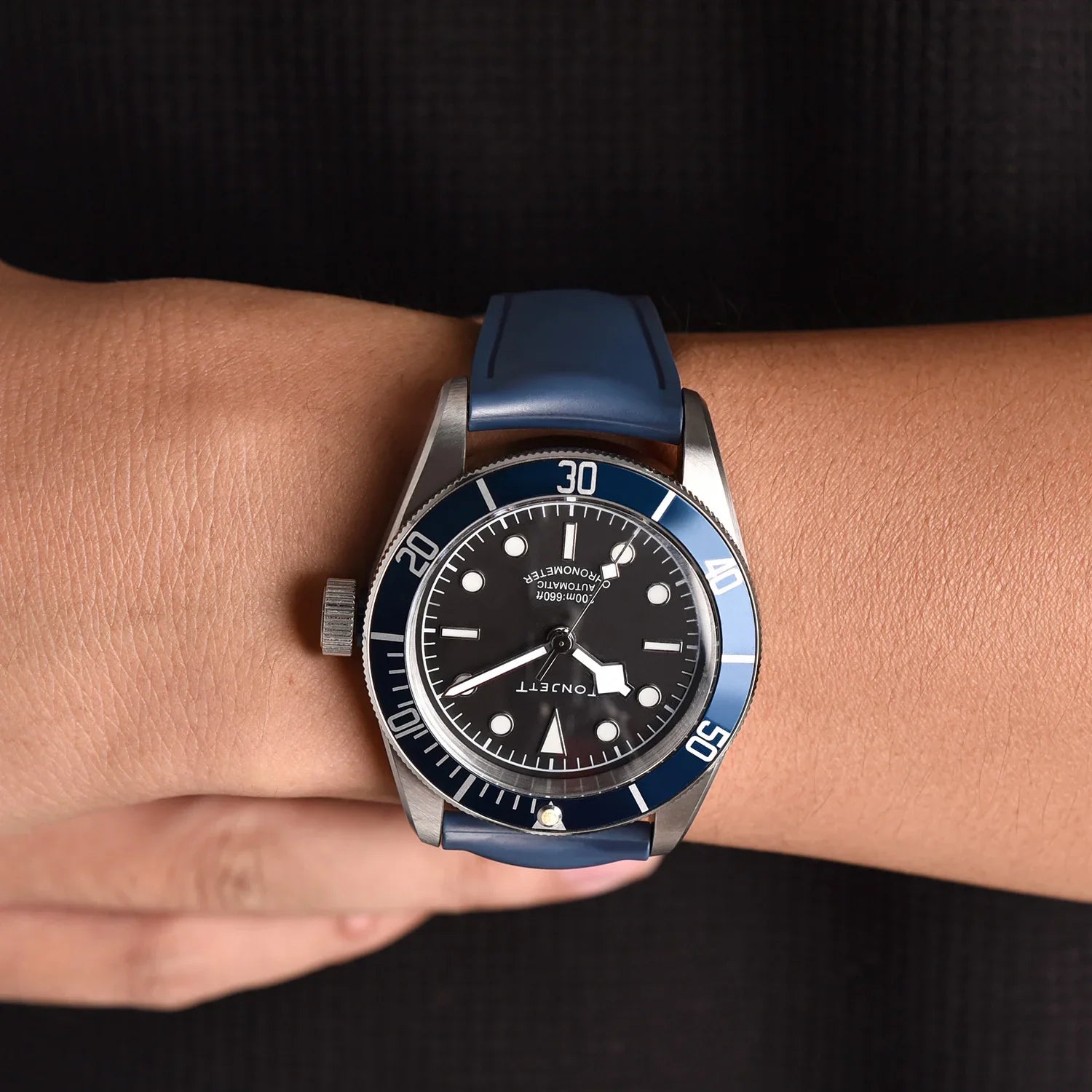 Montre de luxe à cadran noir et lunette bleue sur bracelet silicone, poignet, misterchrono.com