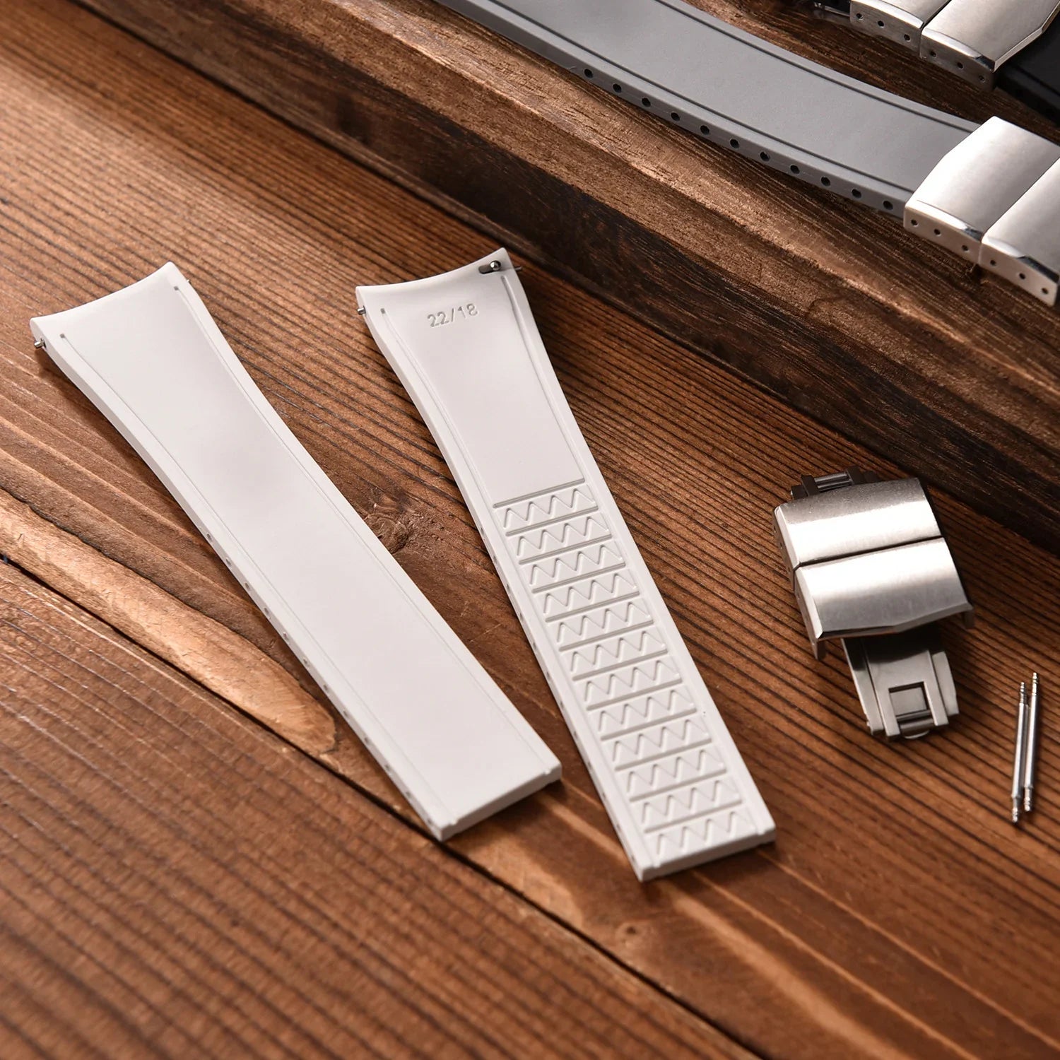 Bracelet de montre blanc en caoutchouc avec boucle déployante, accessoires sur bois.