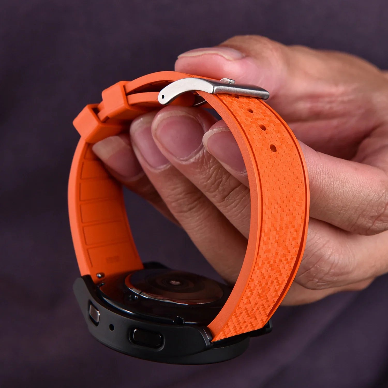 Bracelet de montre orange texturé en silicone, tenu à la main, accessoire pour montre de luxe.