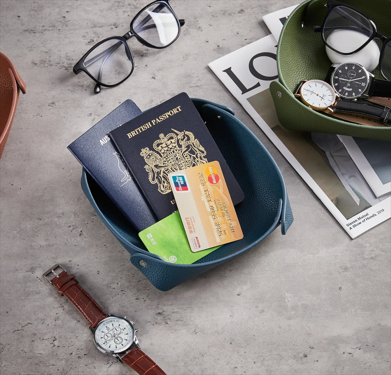 Accessoires pour montres de luxe, garde-temps, lunettes, magazines et passeports sur table grise